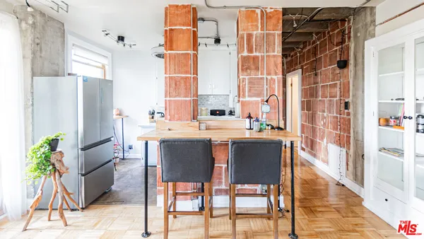 a dining room with stainless steel appliances kitchen island granite countertop a table chairs and a refrigerator