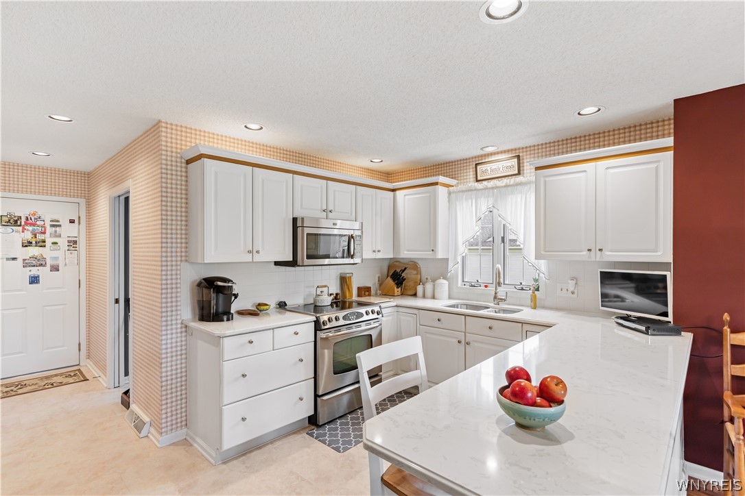 2850 Amsdell Road, Unit 34 Hamburg, NY 14075 - Photo 3 of 33 White cabinetry, stone counters, and a raised breakfast bar create a highly functional kitchen workspace.