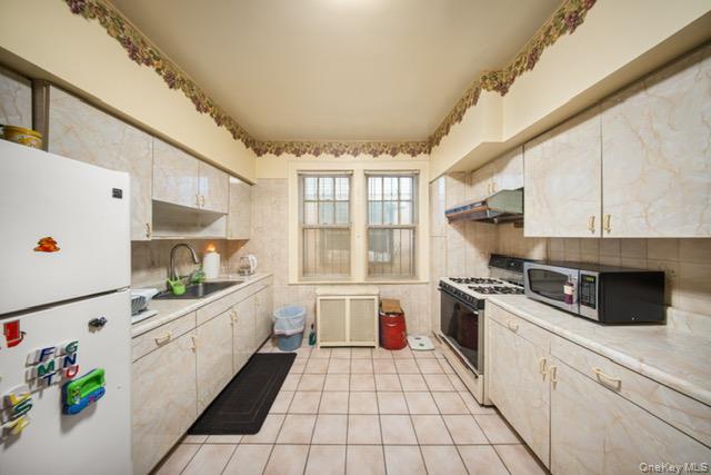 41-71 Gleane Street Queens, NY 11373 - Photo 10 of 28 a kitchen with a stove a sink dishwasher and white cabinets with wooden floor