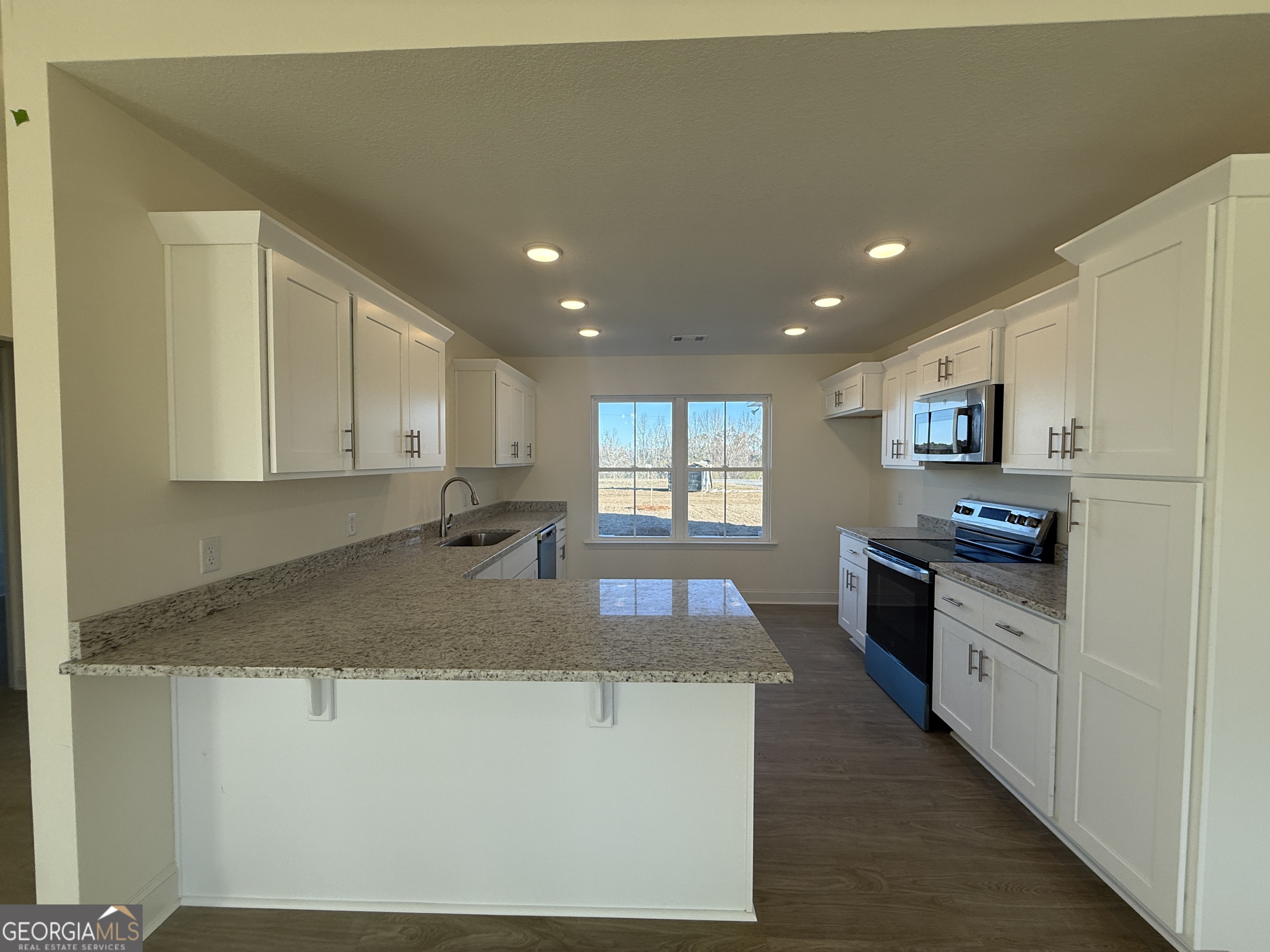 304 Womack Road South Portal, GA 30450 - Photo 6 of 19 a kitchen with kitchen island granite countertop a stove top oven a sink a counter space and cabinets