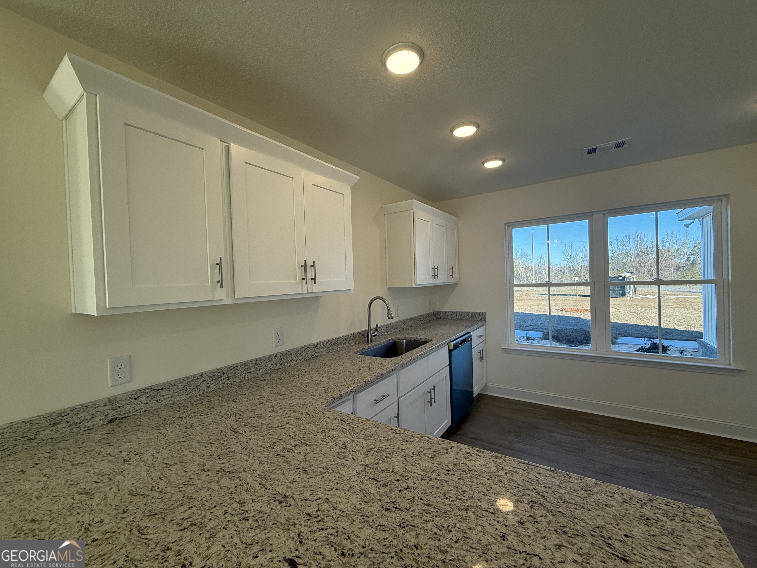 304 Womack Road South Portal, GA 30450 - Photo 8 of 19 a kitchen with granite countertop a sink and white cabinets