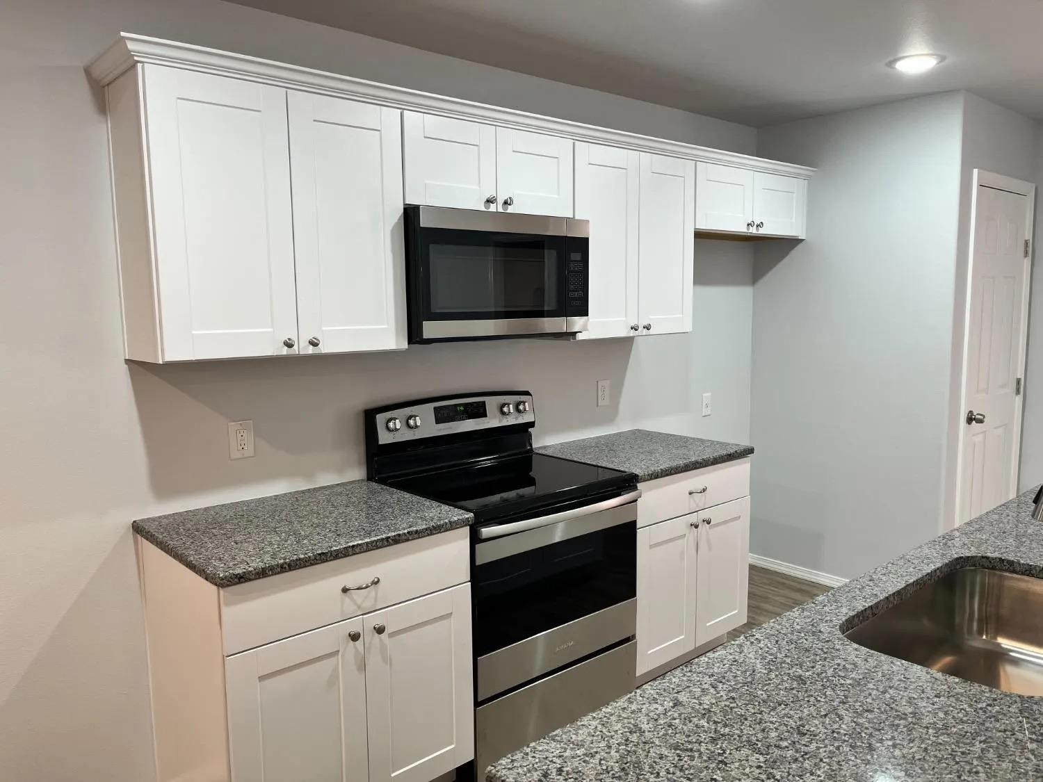 8423 10th Place Lubbock, TX 79416 - Photo 12 of 13 a kitchen with granite countertop white cabinets and black appliances