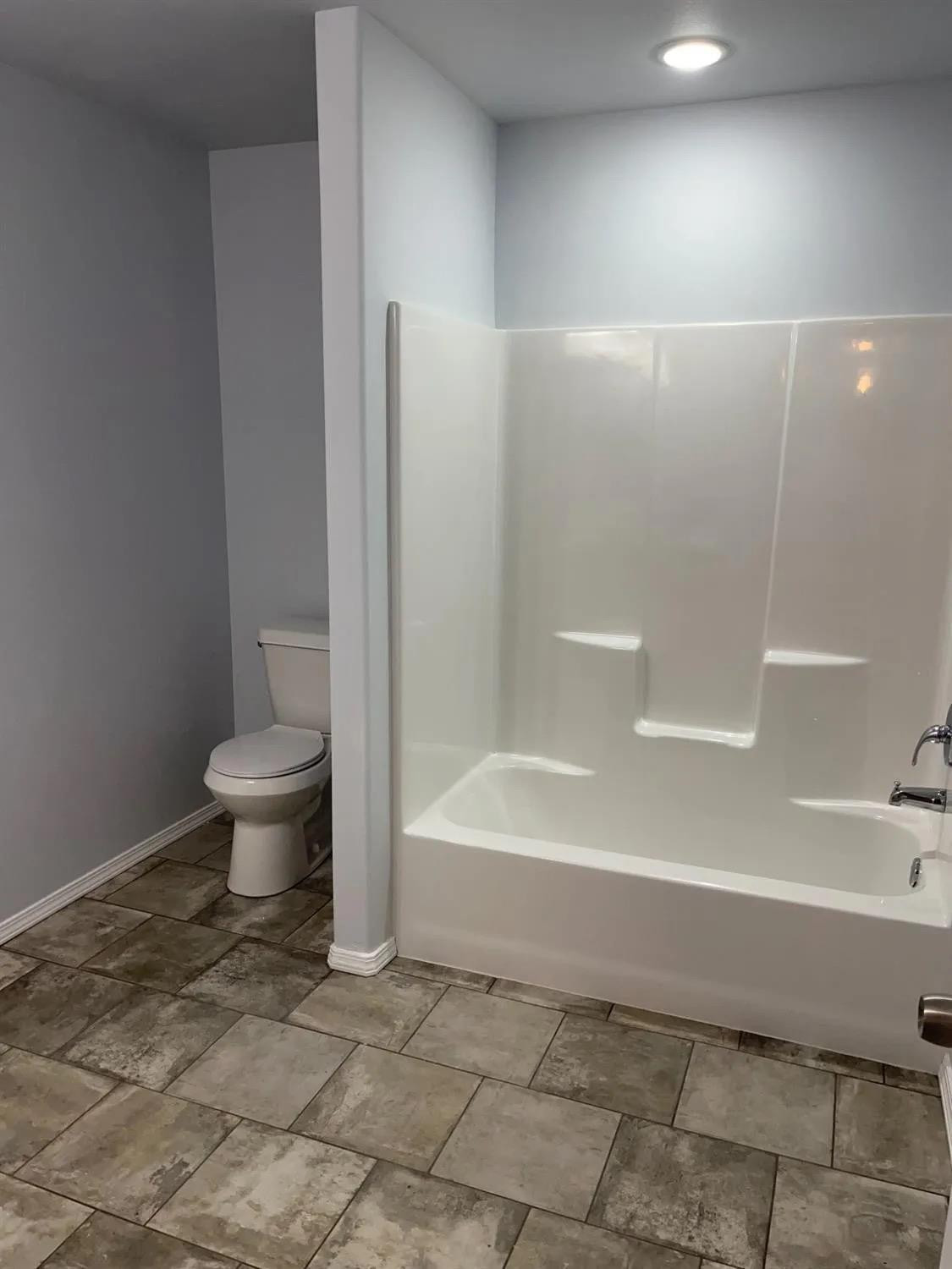 8423 10th Place Lubbock, TX 79416 - Photo 7 of 13 a bathroom with a bathtub and a toilet