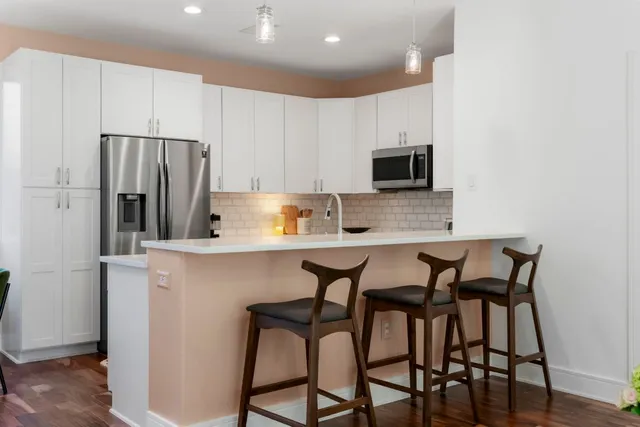 a kitchen with stainless steel appliances granite countertop a table and chairs in it