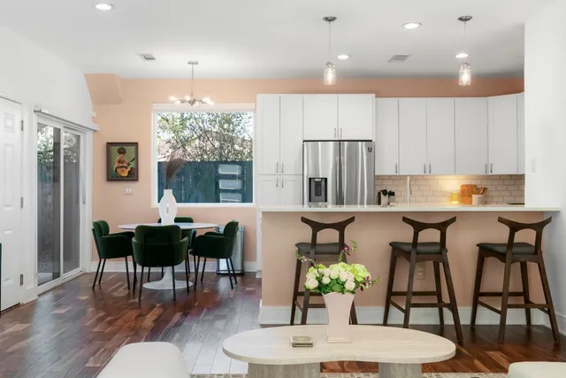 a kitchen with kitchen island granite countertop a dining table chairs and white cabinets