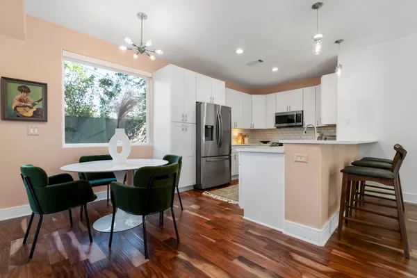 a kitchen with stainless steel appliances granite countertop a stove a refrigerator a kitchen island a dining table and chairs with wooden floor