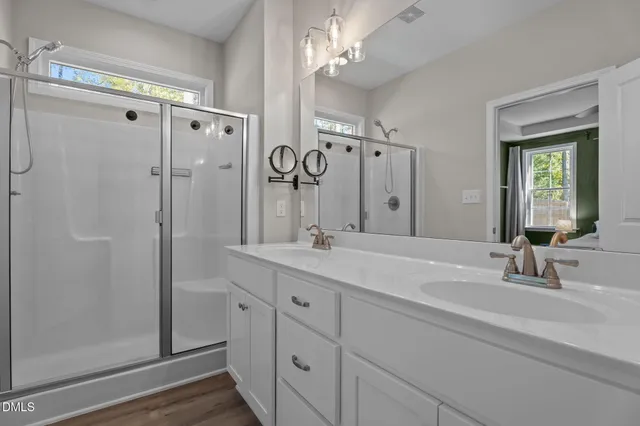 a bathroom with a double vanity sink mirror and shower