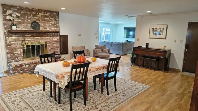 a living room with furniture a fireplace and a dining table with wooden floor