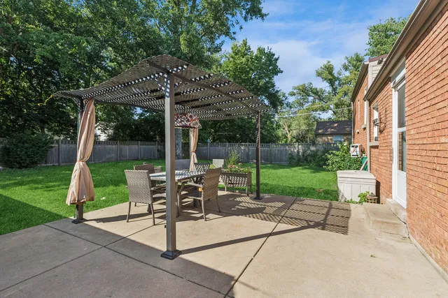 a view of a patio with table and chairs potted plants and large tree