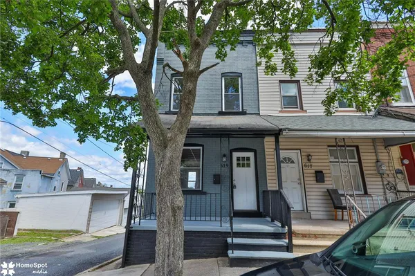a front view of a house with a tree