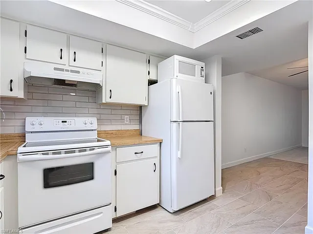 a kitchen with white cabinets sink and window