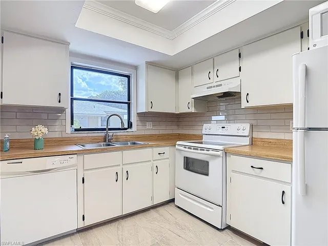 a kitchen with cabinets appliances a sink and a window