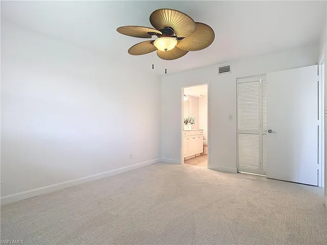 an empty room with windows and chandelier fan