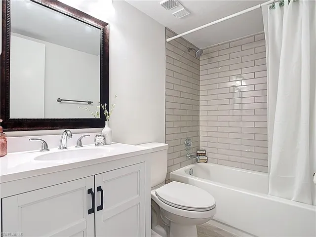 an empty room with a chandelier fan and windows