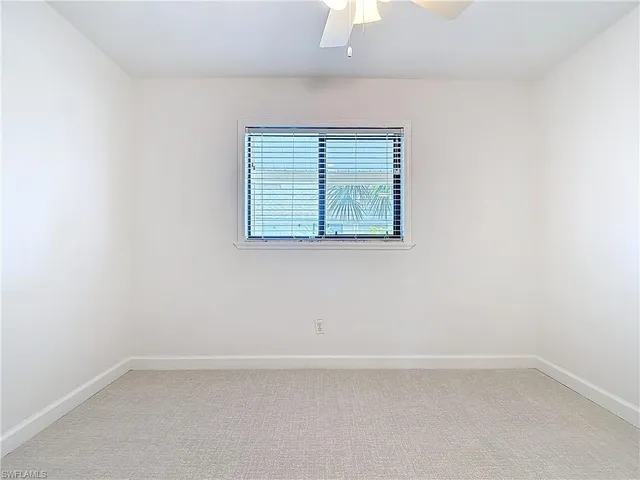 en empty room with windows and chandelier fan