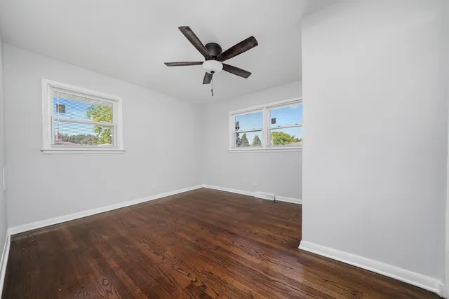 a view of empty room with wooden floor and ceiling fan