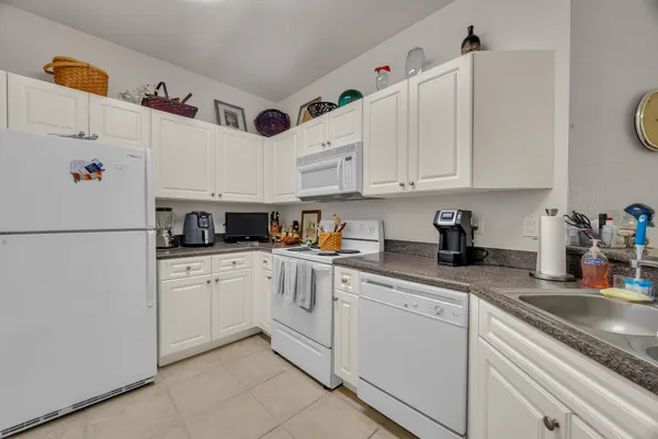 a kitchen with granite countertop white cabinets and white appliances