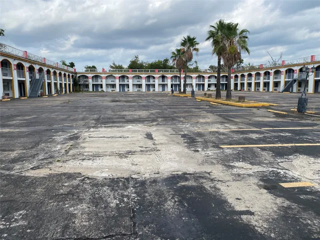 a view of a white house with a swimming pool and lawn chairs