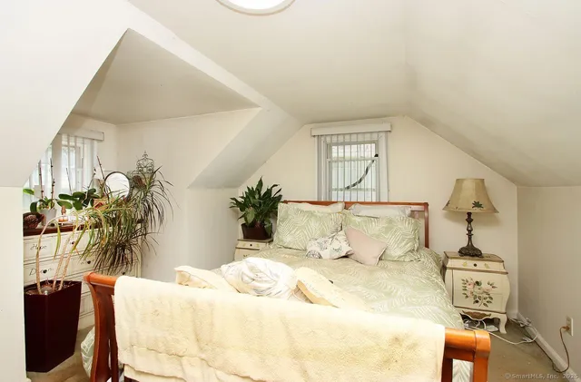 a bed sitting in a bedroom next to a window with potted plant