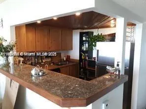 a living room with patio furniture and a dining table with kitchen view