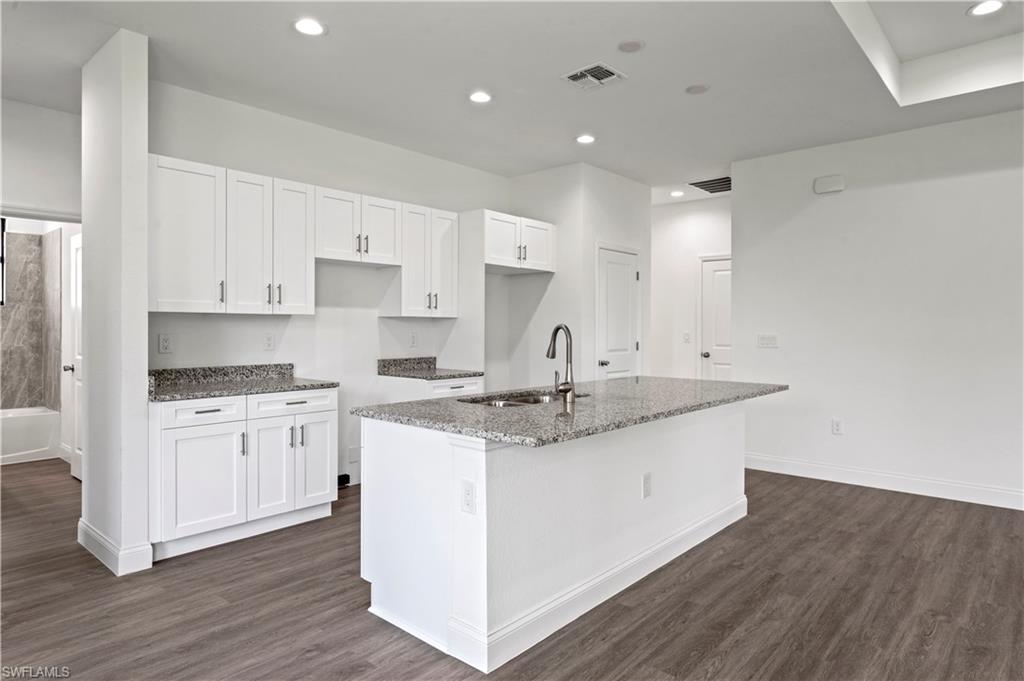 2617 3rd Street Southwest Lehigh Acres, FL 33976 - Photo 5 of 22 a kitchen with stainless steel appliances granite countertop a sink stove and white cabinets with wooden floor