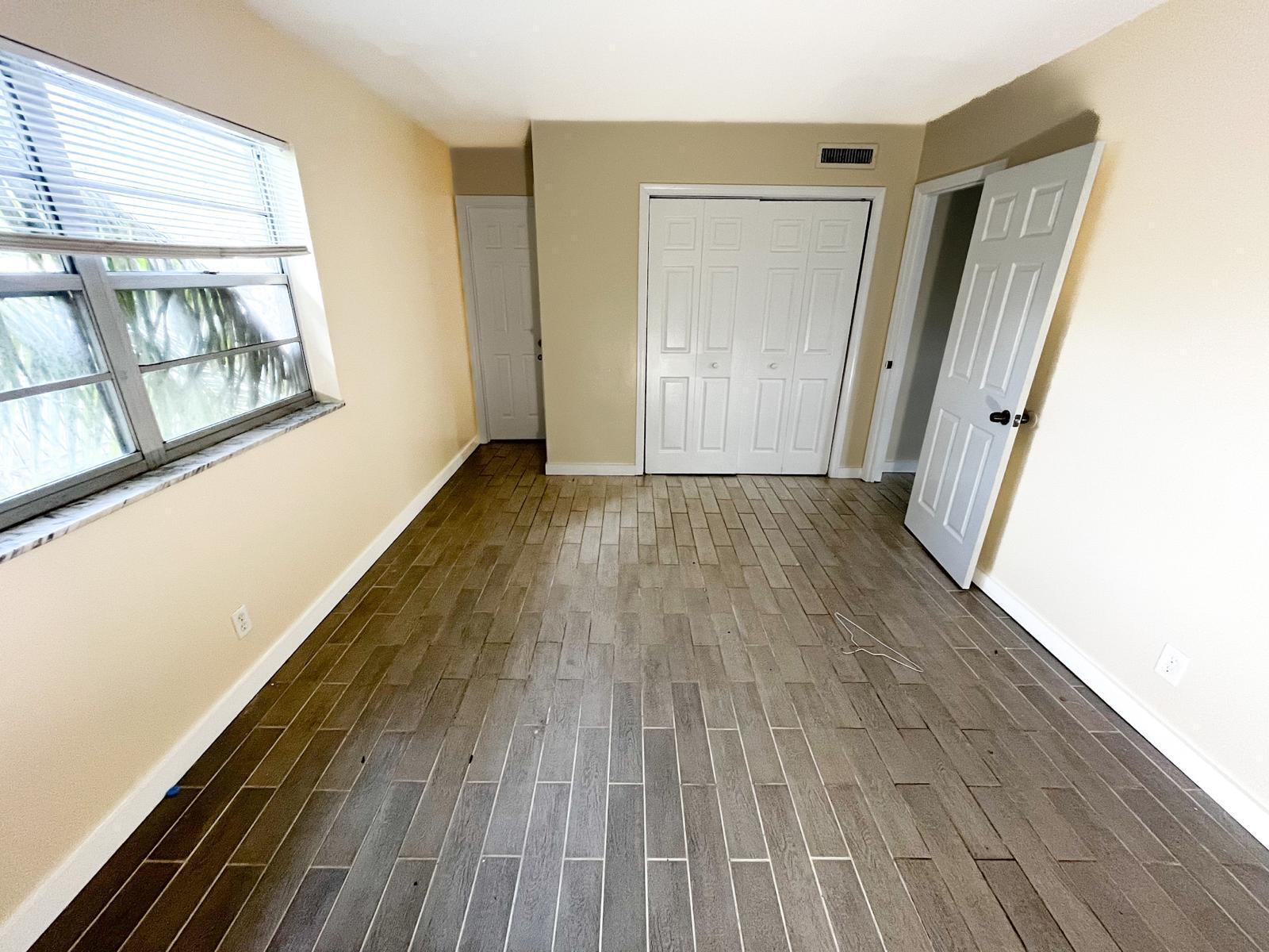 202 Lucerne Avenue, Unit 10 Lake Worth Beach, FL 33460 - Photo 9 of 16 a view of an empty room with wooden floor and a window