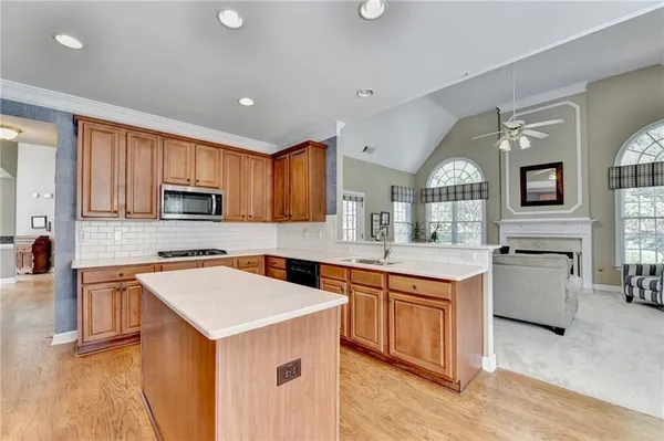 a kitchen with stainless steel appliances granite countertop a stove top oven a sink dishwasher and a refrigerator with wooden floor