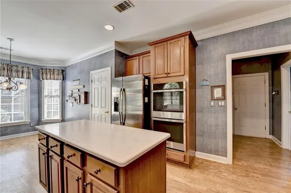 a kitchen with stainless steel appliances a kitchen island hardwood floor and a window