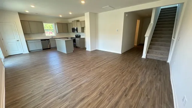 an open kitchen with wooden floor and stainless steel appliances