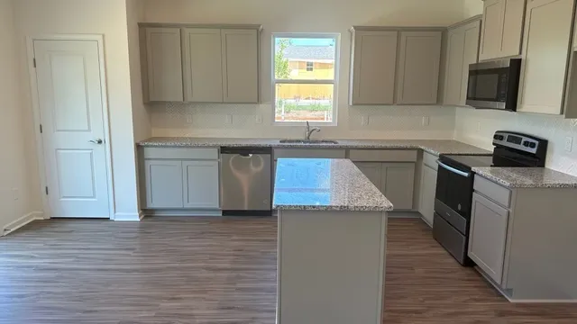 a kitchen with granite countertop a sink a stove and cabinets