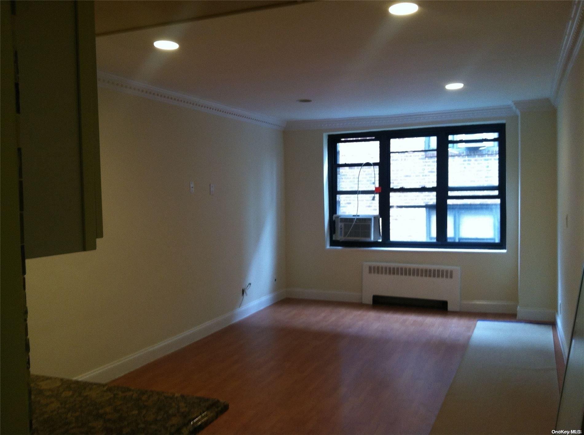 15 Canterbury Road, Unit C13 Great Neck, NY 11021 - Photo 5 of 12 an empty room with wooden floor and windows