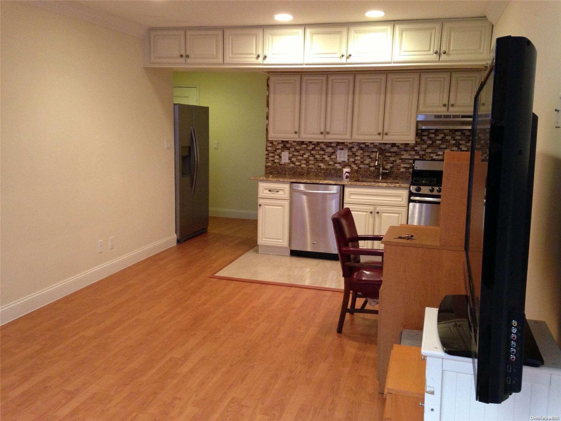 15 Canterbury Road, Unit C13 Great Neck, NY 11021 - Photo 7 of 12 a kitchen with stainless steel appliances kitchen island granite countertop a refrigerator stove and sink