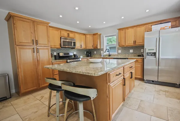 a kitchen with stainless steel appliances granite countertop a stove refrigerator sink and cabinets