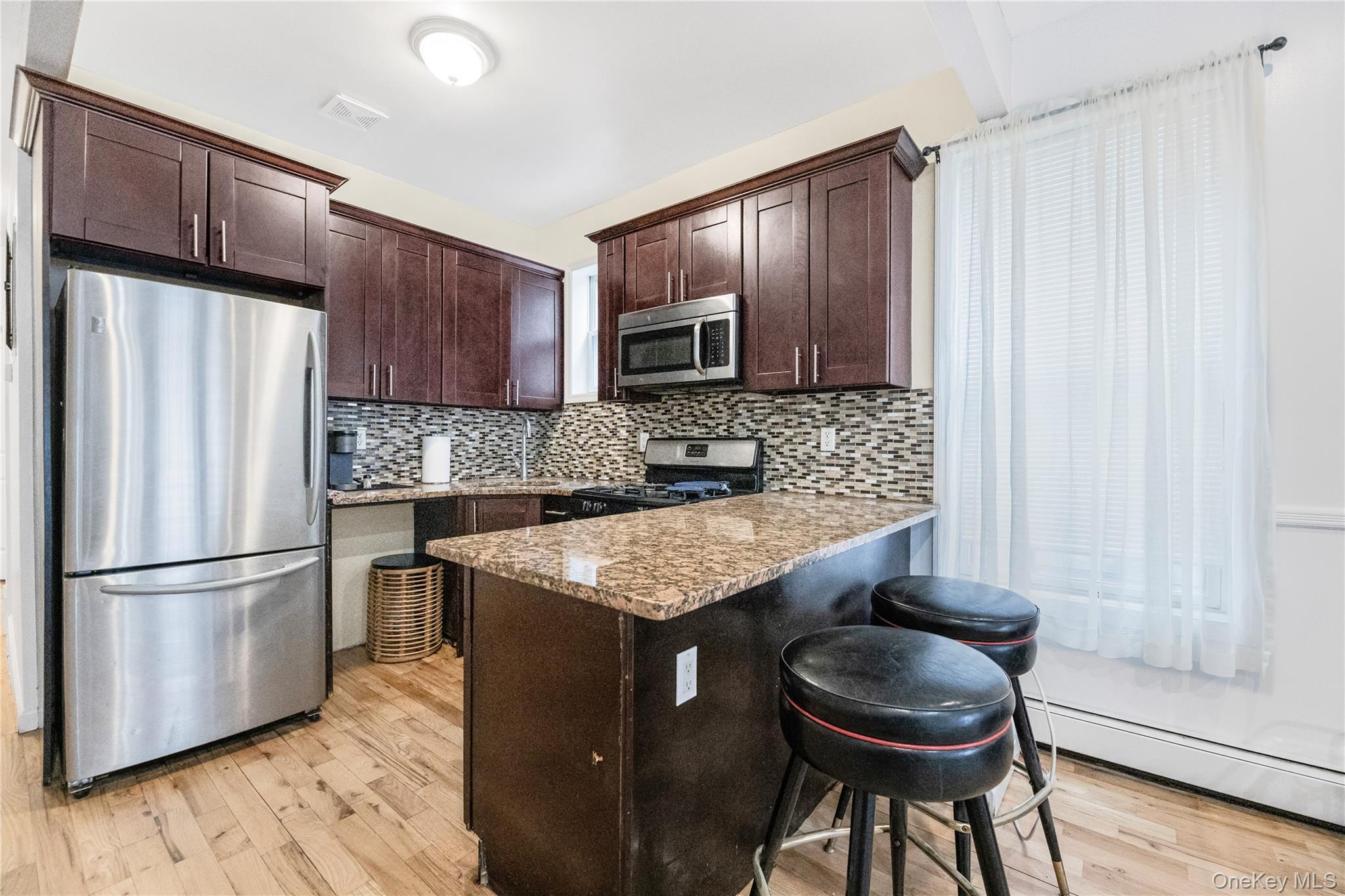 621 Faile Street Bronx, NY 10474 - Photo 22 of 32 a kitchen with granite countertop a stove refrigerator and microwave