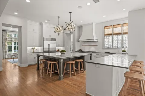 a kitchen with stainless steel appliances kitchen island granite countertop a table chairs sink and cabinets