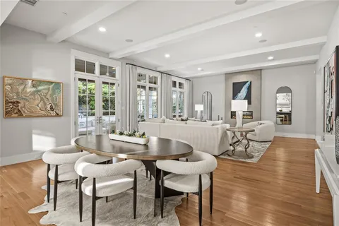a dining room with wooden floor and large windows