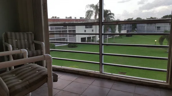 a view of a balcony with two chairs and a book shelf