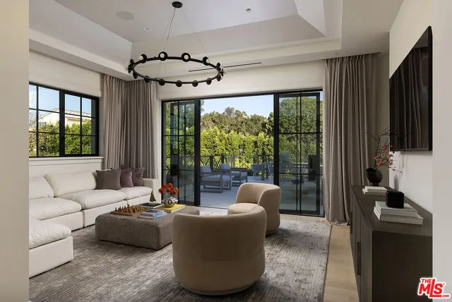 a living room with furniture floor to ceiling window and a flat screen tv