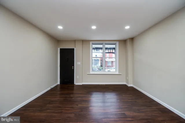 an empty room with wooden floor and window
