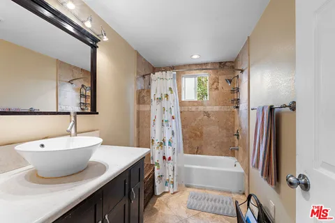 a bathroom with a double vanity sink a mirror a bathtub and shower