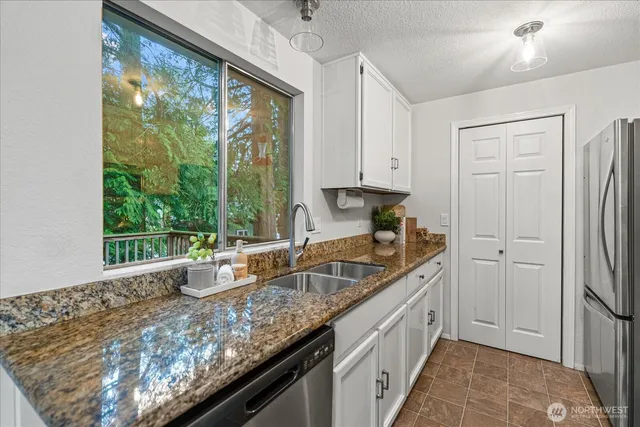 a kitchen with a granite countertop sink and refrigerator