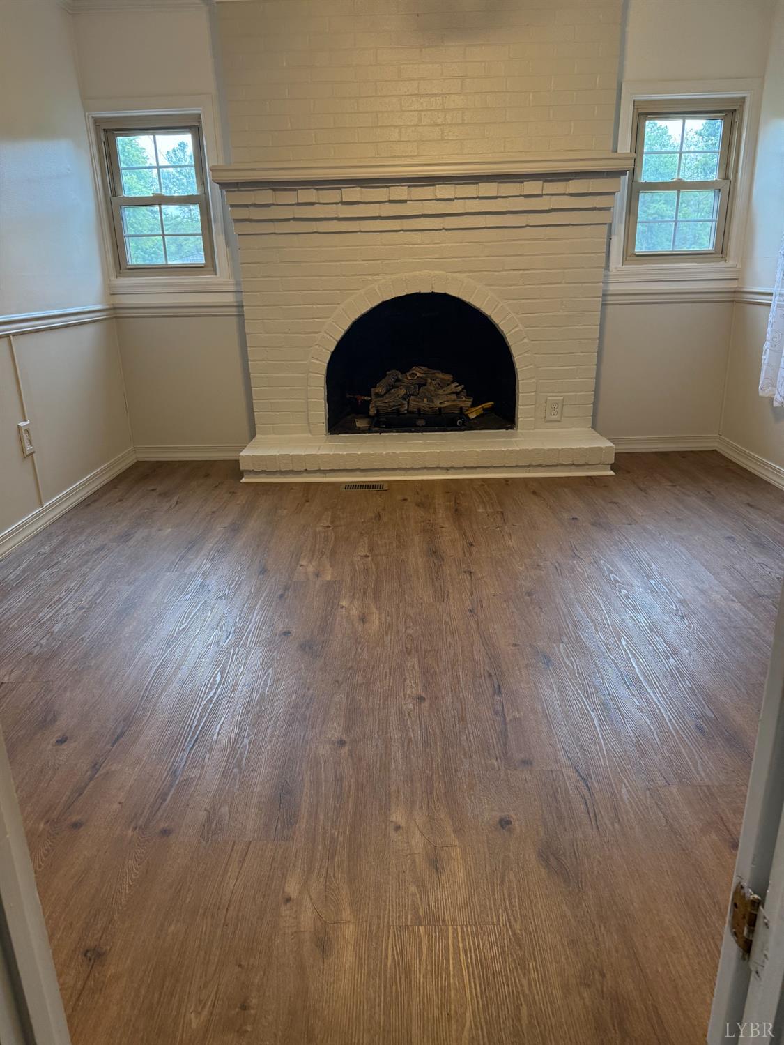 1046 Clarks Road Rustburg, VA 24588 - Photo 3 of 19 an empty room with wooden floor and fireplace