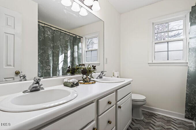 6733 Oviedo Drive Raleigh, NC 27603 - Photo 22 of 33 a bathroom with a double vanity sink toilet and a mirror