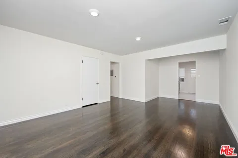 a view of an empty room with wooden floor and closet
