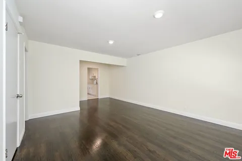 a view of an empty room with wooden floor and closet