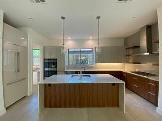 a kitchen with kitchen island granite countertop a sink a counter top space and stainless steel appliances