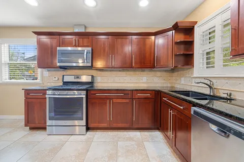 a kitchen with stainless steel appliances granite countertop a stove microwave and sink
