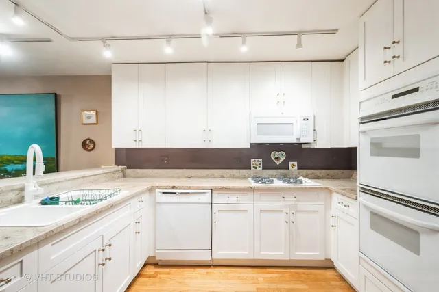 a kitchen with a sink dishwasher stove and white cabinets
