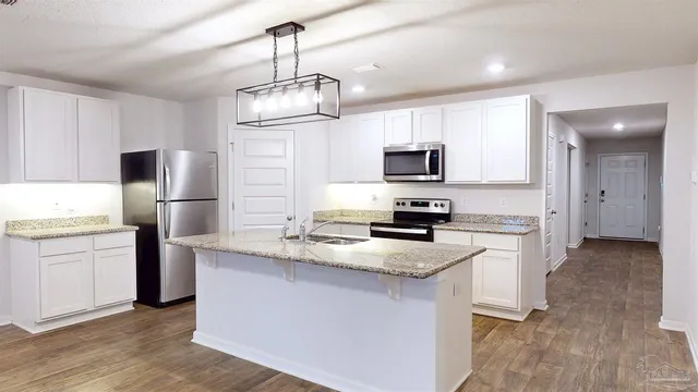 a kitchen with kitchen island granite countertop stainless steel appliances cabinets a sink and a refrigerator