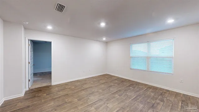 an empty room with wooden floor and windows